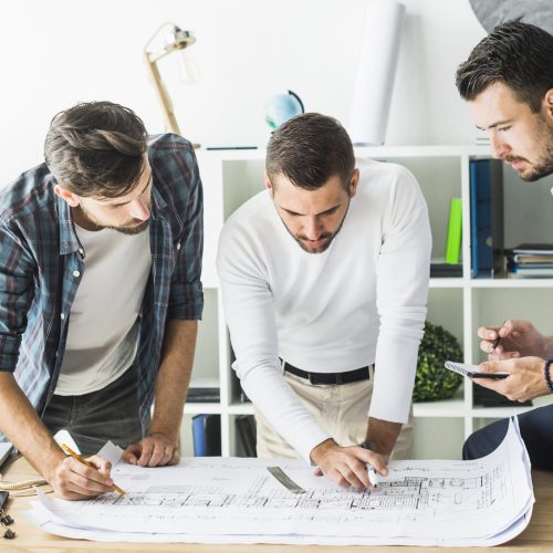 group-male-architect-analyzing-blueprint